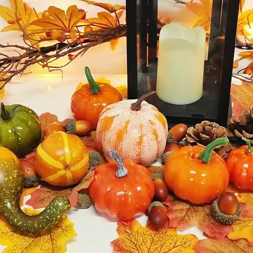 Autumn decor with pumpkins, leaves, and candle.