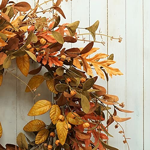 Autumn wreath with orange leaves and berries on wooden background.