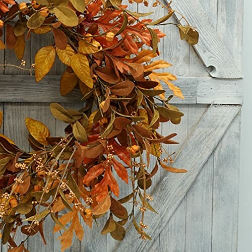 Autumn wreath with orange and brown leaves on a wooden door.