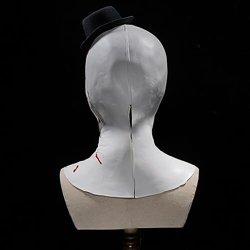 Back view of a white mask with a small black hat.