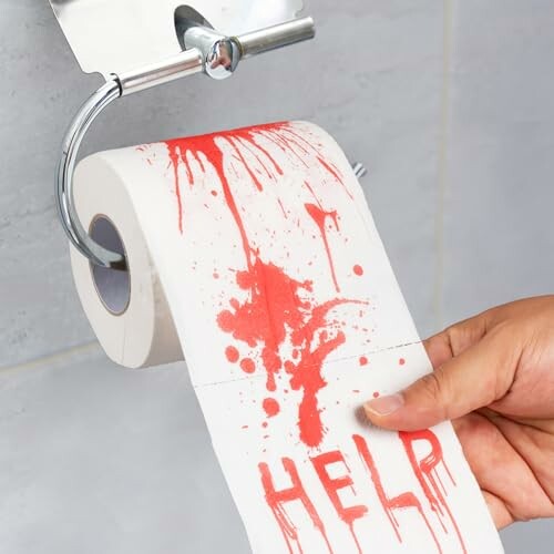 Toilet paper roll with red paint resembling blood and the word 'HELP'.