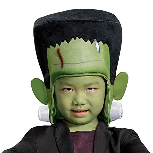 Child wearing a Frankenstein costume hat with green face paint.