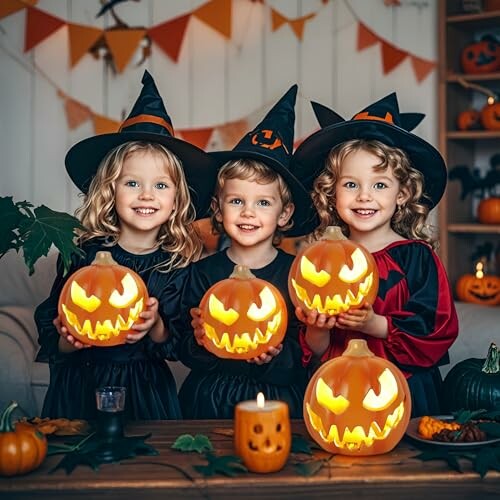 Three children in witch costumes holding carved pumpkins.