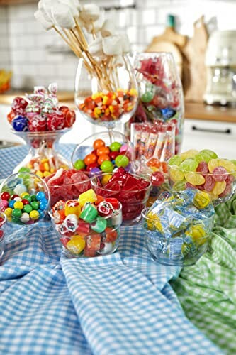 Assorted colorful candies in glass bowls on a checkered cloth.