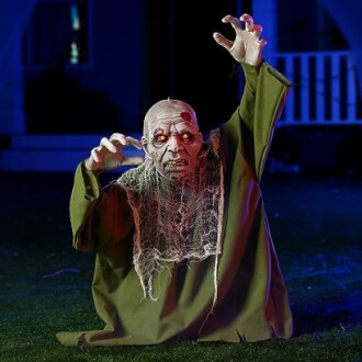 Creepy zombie decoration with glowing eyes and green robe