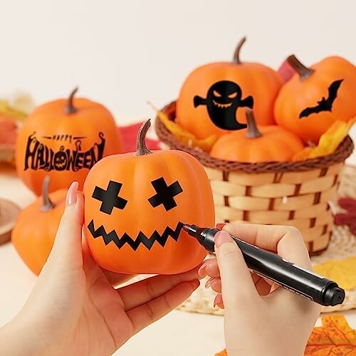 Person decorating small pumpkins with Halloween designs.