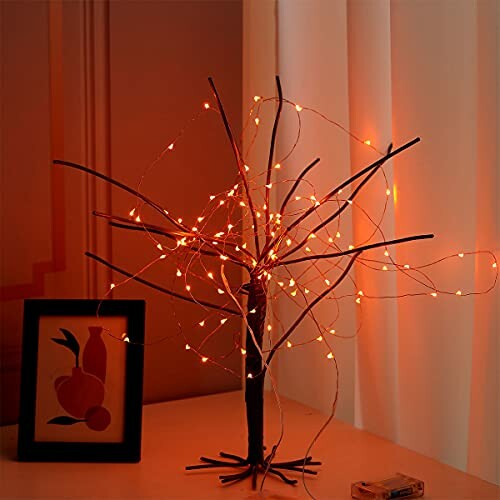 Decorative LED tree light with orange glow on a table.