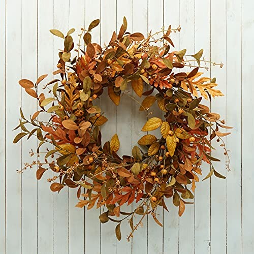 Autumn wreath with orange and brown leaves on a wooden wall.