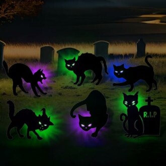 Silhouettes of glowing black cats with tombstones in a graveyard at night.