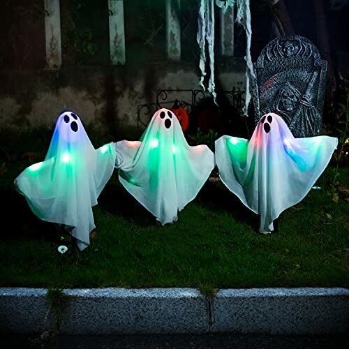 Three glowing ghost decorations on grass