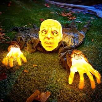 Glowing zombie decoration on grass with lit hands.