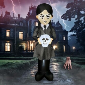 Gothic figure holding a skull in front of a haunted mansion with lightning.