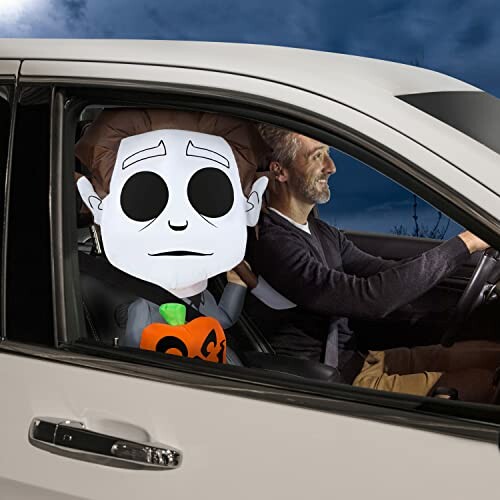 Driver with Halloween character decoration in car passenger seat.