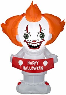 Inflatable clown with orange hair holding 'Happy Halloween' sign.