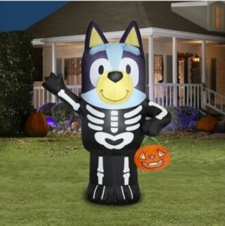 Inflatable dog in skeleton costume holding pumpkin bucket on lawn