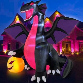 Inflatable dragon with pumpkin decoration in front of illuminated house