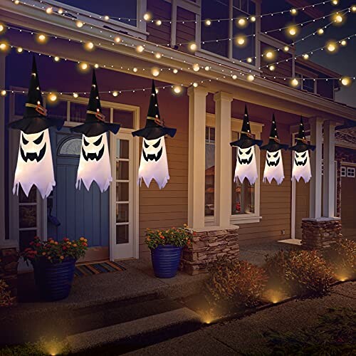 Halloween ghost decorations hanging outside a house with lights.