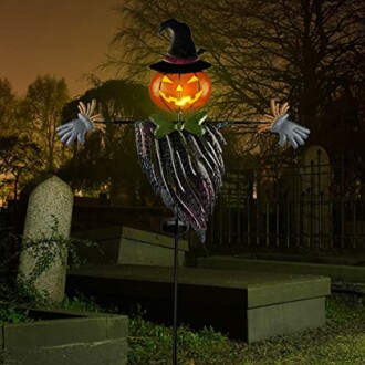 Halloween jack-o-lantern scarecrow with witch hat in a graveyard