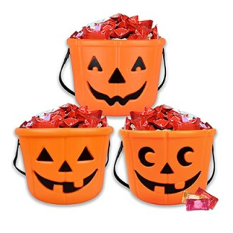 Three orange pumpkin buckets filled with candy.