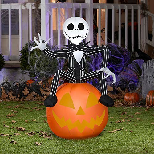 Inflatable Halloween decoration with a skeleton figure sitting on a pumpkin in a yard.