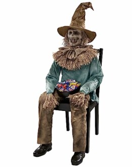 Halloween scarecrow decoration holding candy on a chair.