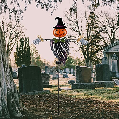 Halloween scarecrow with pumpkin head in cemetery