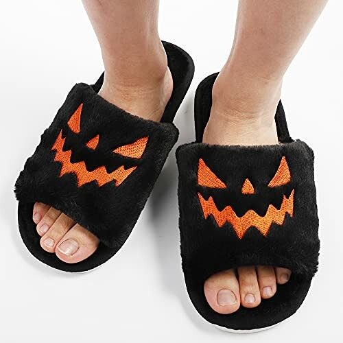 Fuzzy black slippers with orange jack-o-lantern faces.