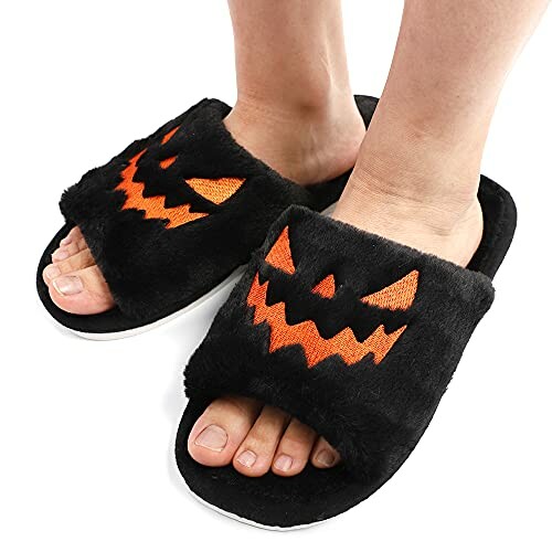 Person wearing black slippers with orange Halloween faces