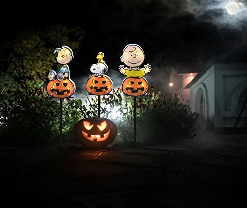 Halloween yard decorations with cartoon characters on pumpkins and a jack-o'-lantern.