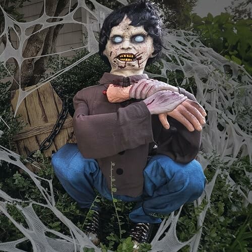 Creepy zombie decoration with a severed arm in an outdoor Halloween setting.