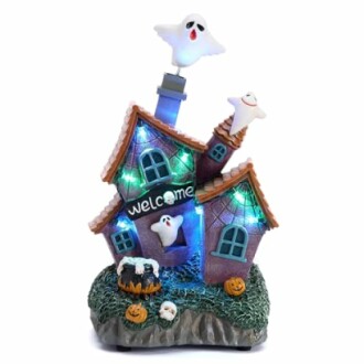 Decorative haunted house with ghosts and pumpkins, illuminated with colorful lights.