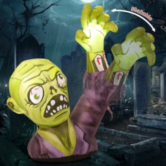 Inflatable zombie decoration with glowing hands in a graveyard setting.