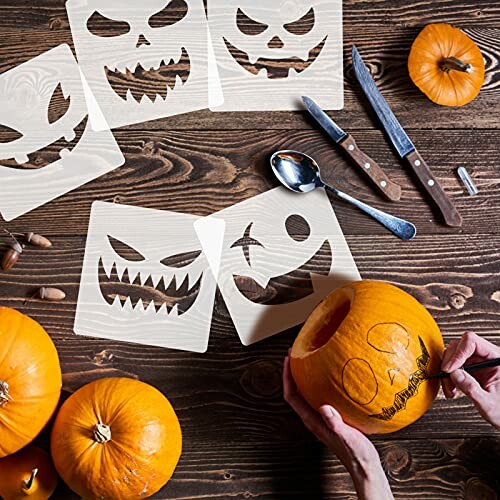 Person carving pumpkin with Halloween stencils on a wooden table.