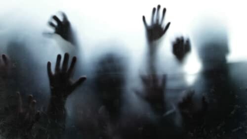 Silhouetted hands pressed against foggy glass.