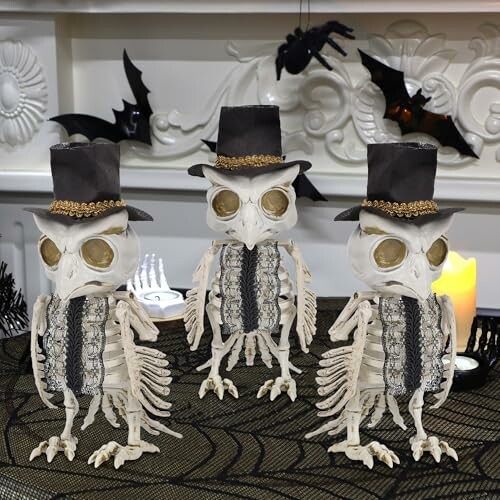 Three skeleton owl decorations with top hats on a table.