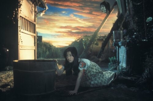 Woman in a fantasy setting with dramatic sunset sky.